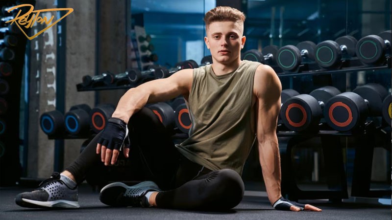 A man in front of the dumbbells at the gym 
